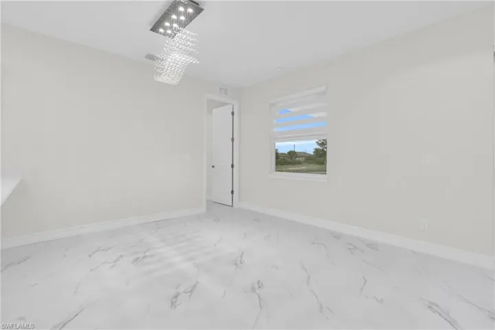 Spare room with marble finish floors and a chandelier