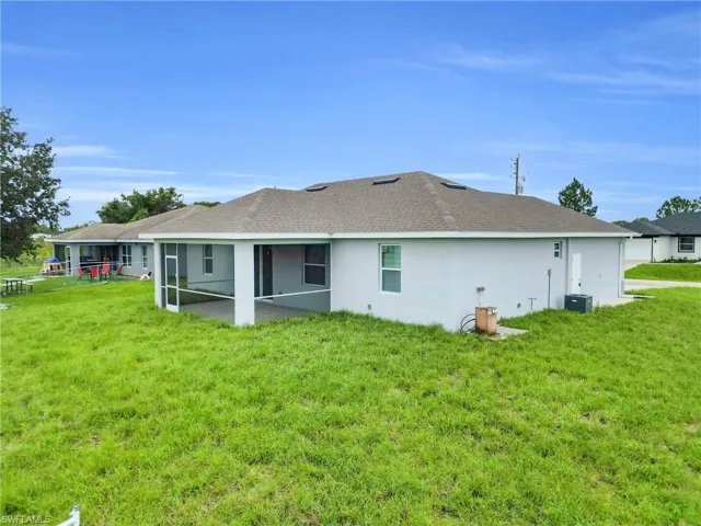 Back of property featuring a sunroom, a yard, roof with shingles, and stucco siding