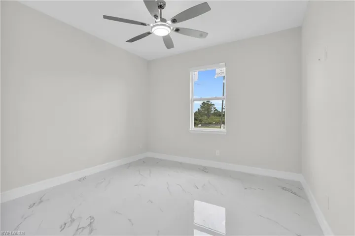 Empty room featuring marble look tile flooring and ceiling fan