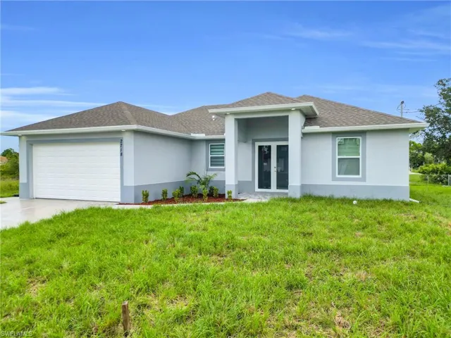 View of front of house featuring french doors, stucco siding, an attached garage, and a front lawn