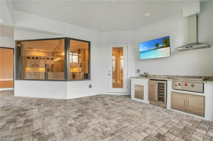 Kitchen featuring wall chimney exhaust hood, wine cooler, and sink