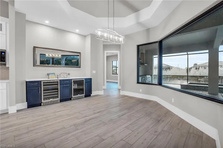 Bar featuring wine cooler, pendant lighting, and plenty of natural light