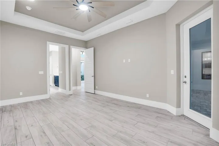 Unfurnished room with ceiling fan, light hardwood / wood-style floors, and a raised ceiling