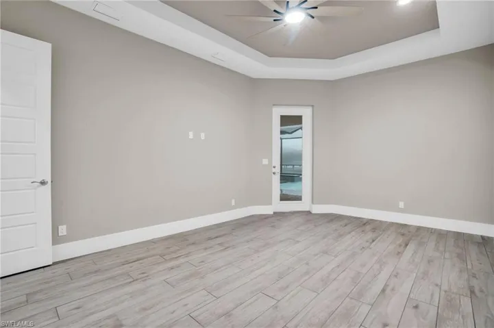 Unfurnished room featuring ceiling fan, light hardwood / wood-style floors, and a raised ceiling