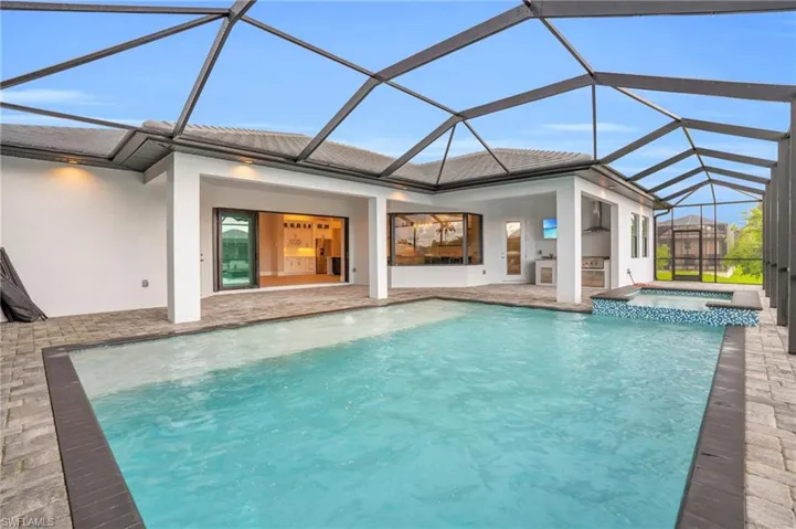 View of pool featuring an in ground hot tub, a patio area, and a lanai