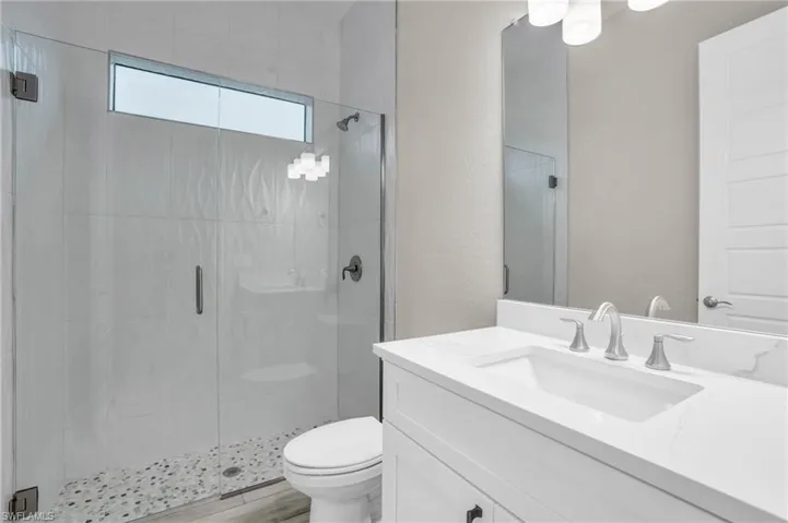 Bathroom featuring vanity, toilet, a shower with shower door, and hardwood / wood-style floors