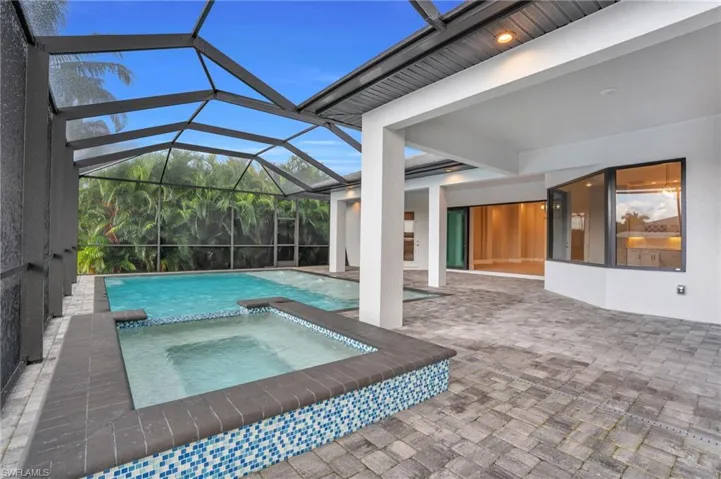 View of swimming pool with an in ground hot tub, a patio area, and a lanai