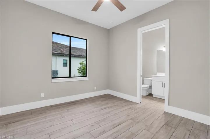 Unfurnished bedroom with connected bathroom, light hardwood / wood-style floors, and ceiling fan