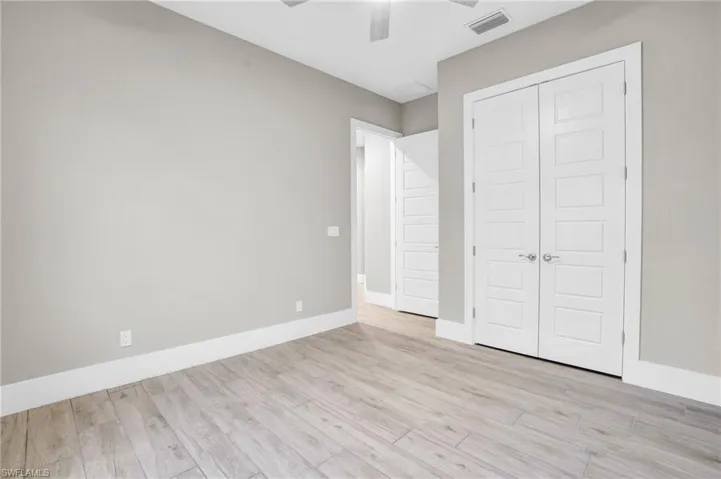 Unfurnished bedroom with a closet, light hardwood / wood-style floors, and ceiling fan