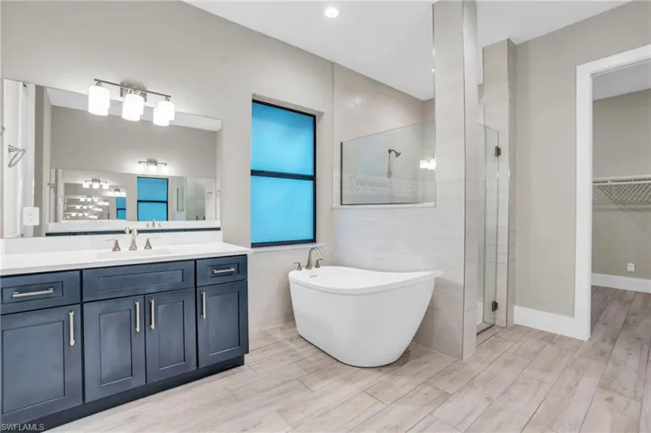 Bathroom with vanity, hardwood / wood-style floors, shower with separate bathtub, and tile walls