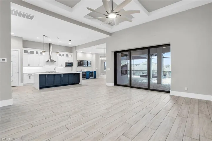 Unfurnished living room featuring light hardwood / wood-style floors, sink, and ceiling fan with notable chandelier