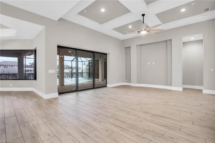 Unfurnished room with light hardwood / wood-style floors, beam ceiling, coffered ceiling, and ceiling fan