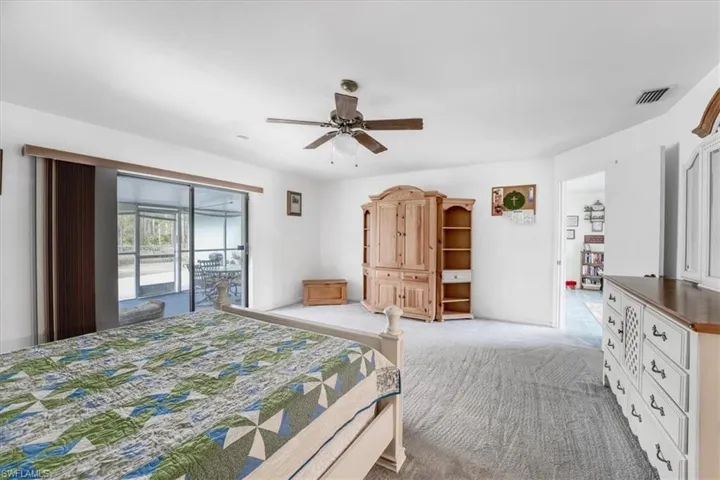 Bedroom with ceiling fan, light carpet, and access to outside