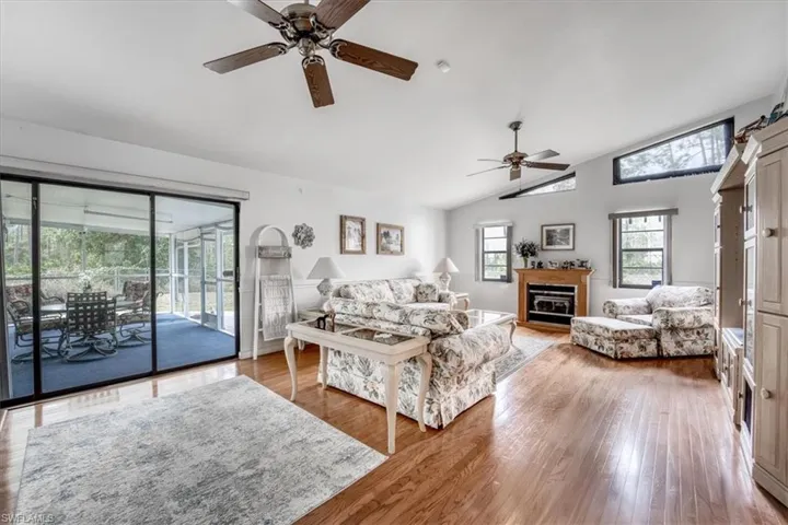 Living room featuring light hardwood floors ceiling fan, and lofted ceiling