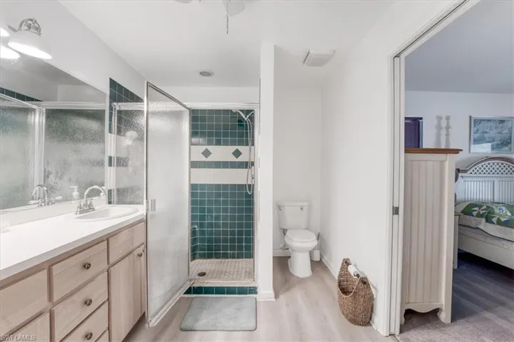 Bathroom featuring toilet, an enclosed shower, wood-type flooring, and vanity