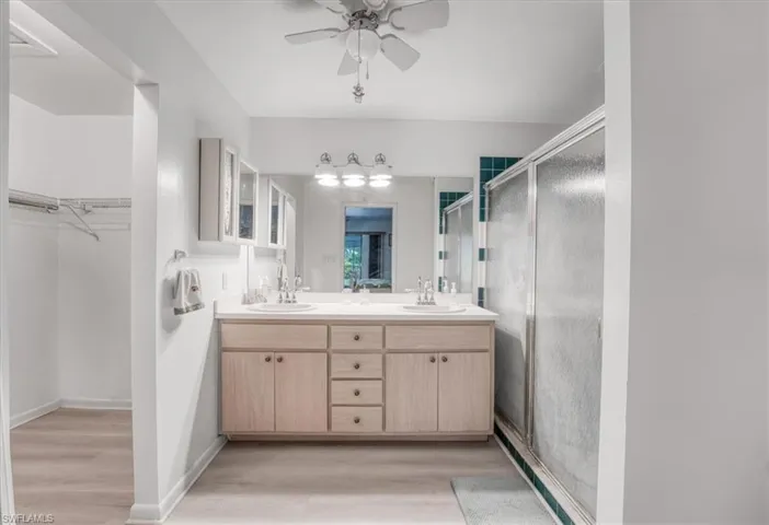 Bathroom featuring wood-style flooring, ceiling fan, an enclosed shower, and vanity