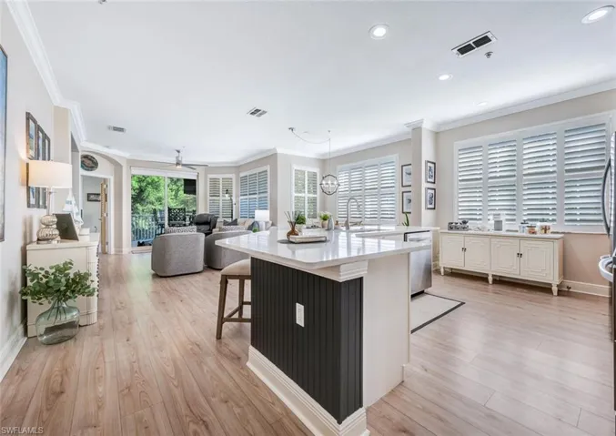 Kitchen featuring decorative light fixtures, light hardwood / wood-style flooring, dishwasher, a kitchen bar, and sink