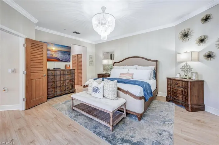 Bedroom with crown molding, an inviting chandelier, and light hardwood / wood-style flooring