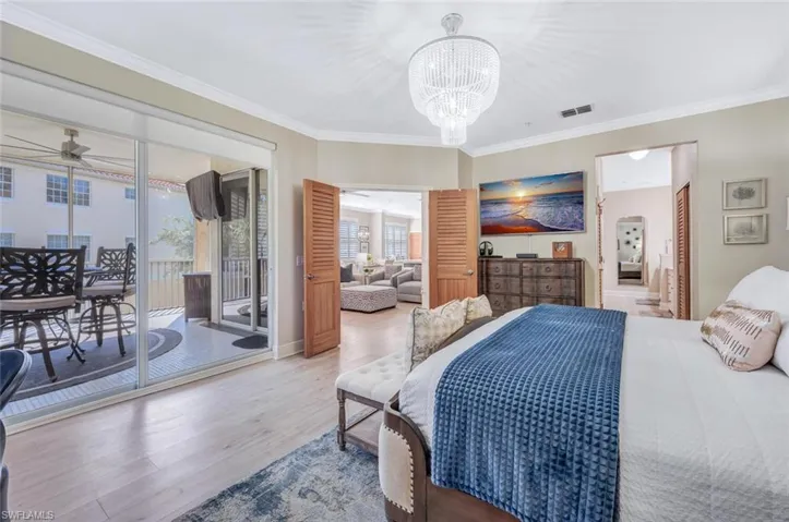 Bedroom featuring access to exterior, crown molding, hardwood / wood-style flooring, and a chandelier