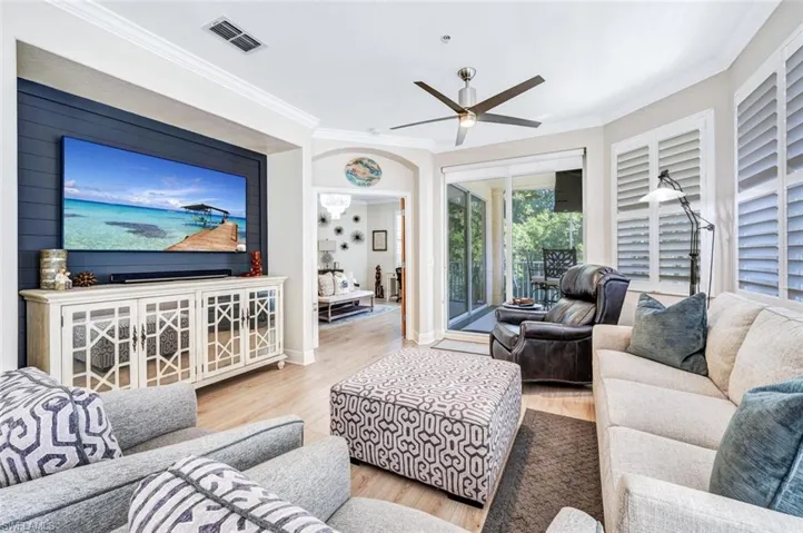 Living room with ceiling fan, light wood-type flooring, and crown molding