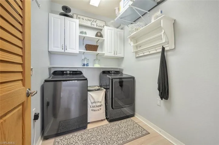 Washroom featuring washer and dryer, cabinets, and light hardwood / wood-style flooring