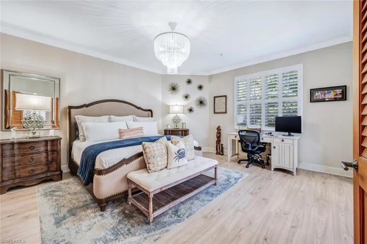Bedroom featuring a notable chandelier, light wood-type flooring, and crown molding