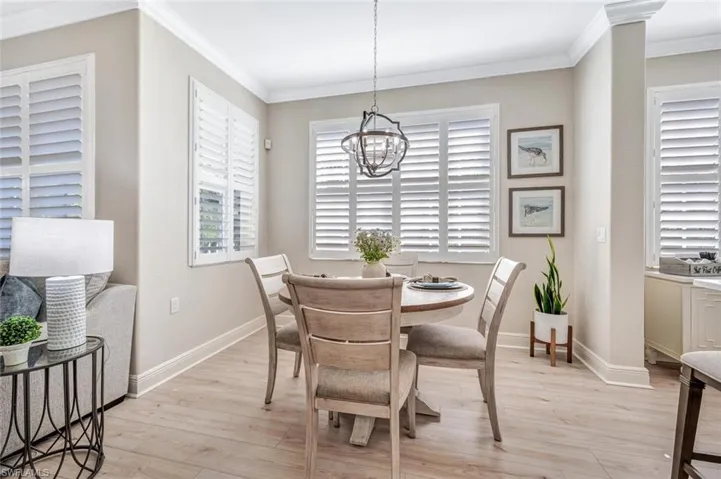 Dining space with crown molding, a chandelier, and light hardwood / wood-style flooring