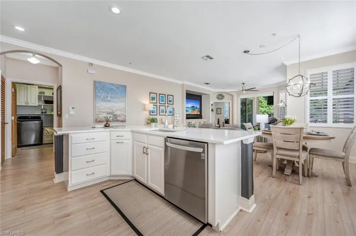Kitchen featuring light hardwood / wood-style floors, hanging light fixtures, ceiling fan with notable chandelier, stainless steel dishwasher, and sink