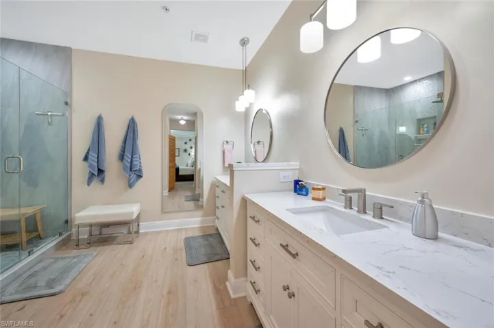 Bathroom with a shower with shower door, hardwood / wood-style floors, and vanity