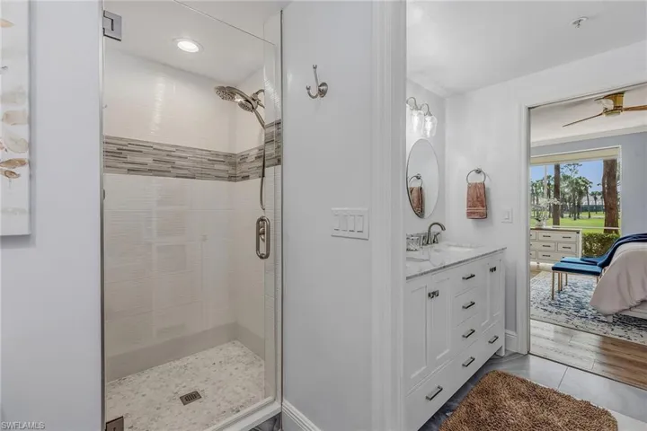 Ensuite bathroom featuring vanity, ceiling fan, a stall shower, and wood finished floors