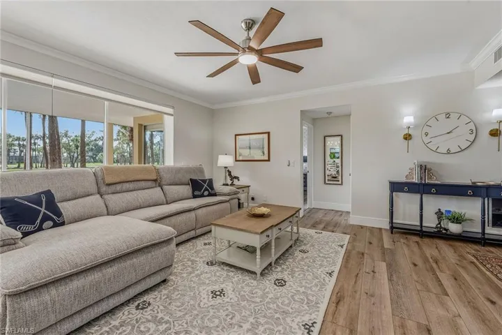 Living area with crown molding, light wood-style floors, and ceiling fan