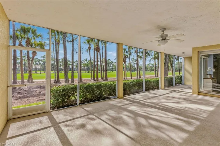 Unfurnished sunroom with ceiling fan and golf course view