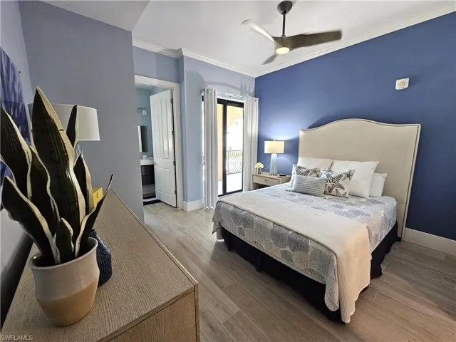 Bedroom with crown molding, wood finished floors, access to exterior, ceiling fan, and ensuite bath