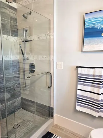 Full bathroom featuring a shower stall and baseboards
