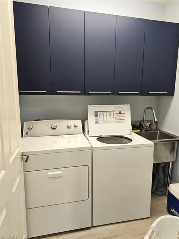 Laundry room with cabinet space, washer and clothes dryer, and light wood finished floors