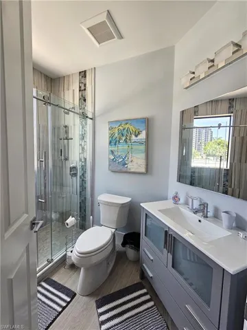 Full bath featuring vanity, light wood-style floors, and a stall shower