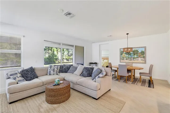 Large sectional sofa fits in this living room space perfectly. Behind it is a dining room table and light