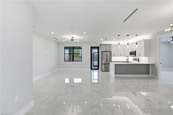 Unfurnished living room with a chandelier and light marble finish floors