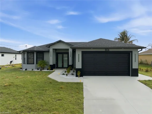 View of front facade featuring roof with shingles, stucco siding, a garage, and a front yard