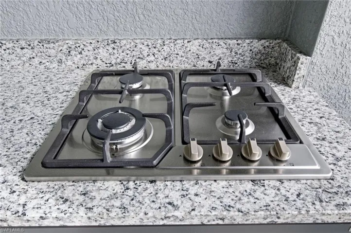 Kitchen view of stainless steel gas stovetop and light stone counters