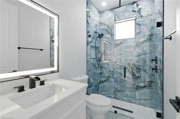 Full bath featuring a marble finish shower and vanity