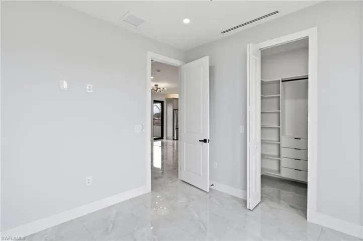 Unfurnished bedroom with recessed lighting and light marble finish flooring