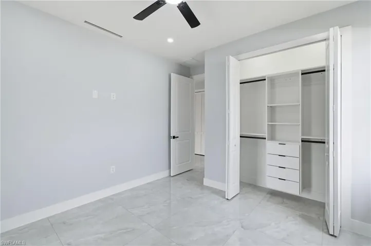 Unfurnished bedroom featuring a ceiling fan, a closet, light marble finish flooring, and recessed lighting
