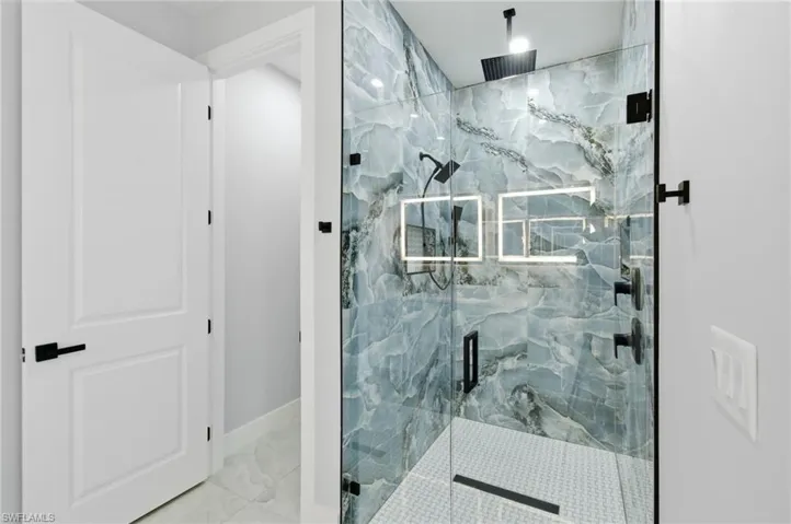 Full bathroom featuring a marble finish shower and baseboards