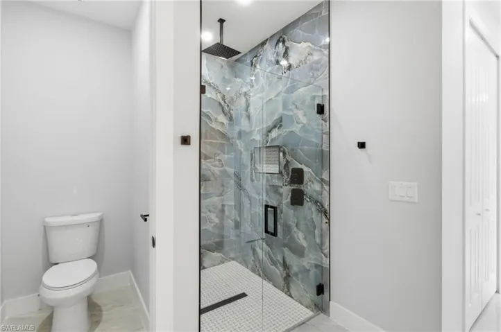 Bathroom with a marble finish shower and light marble finish floors