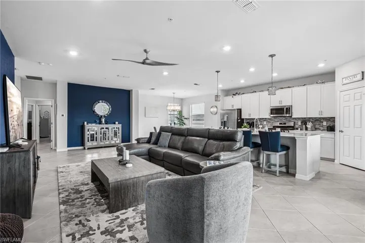 Living area featuring ceiling fan, light tile patterned floors, recessed lighting, and a chandelier