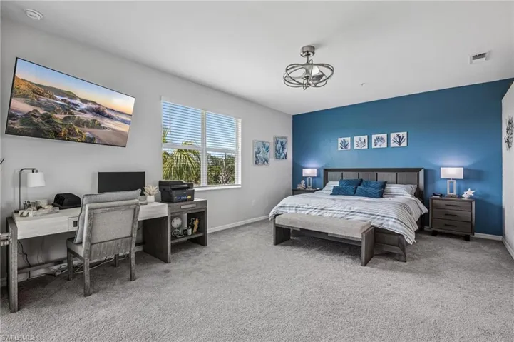 Carpeted bedroom featuring an office area and a chandelier