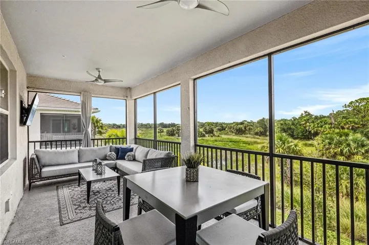 Sunroom with a ceiling fan, an outdoor hangout area, and view of wooded area