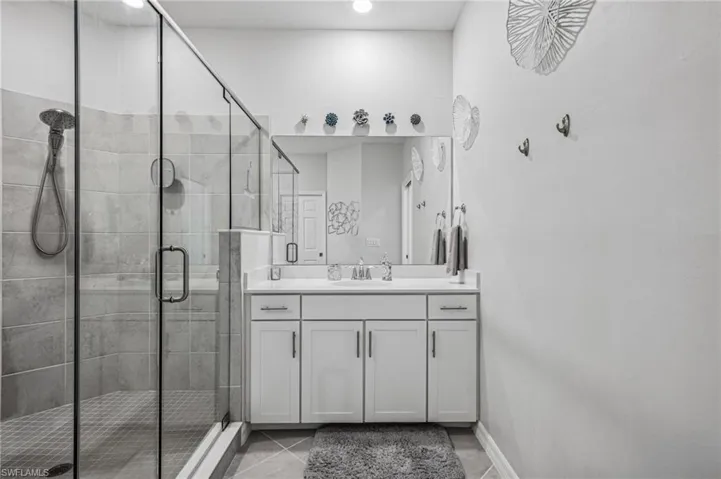 Full bathroom with tile patterned flooring, vanity, a shower stall, and recessed lighting
