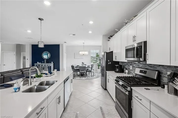 Kitchen with appliances with stainless steel finishes, light countertops, white cabinetry, decorative backsplash, and recessed lighting